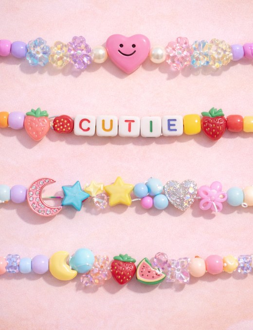 Close-up of an organized charm bracelet station with beads sorted in small bowls and charms laid out on a pastel cloth