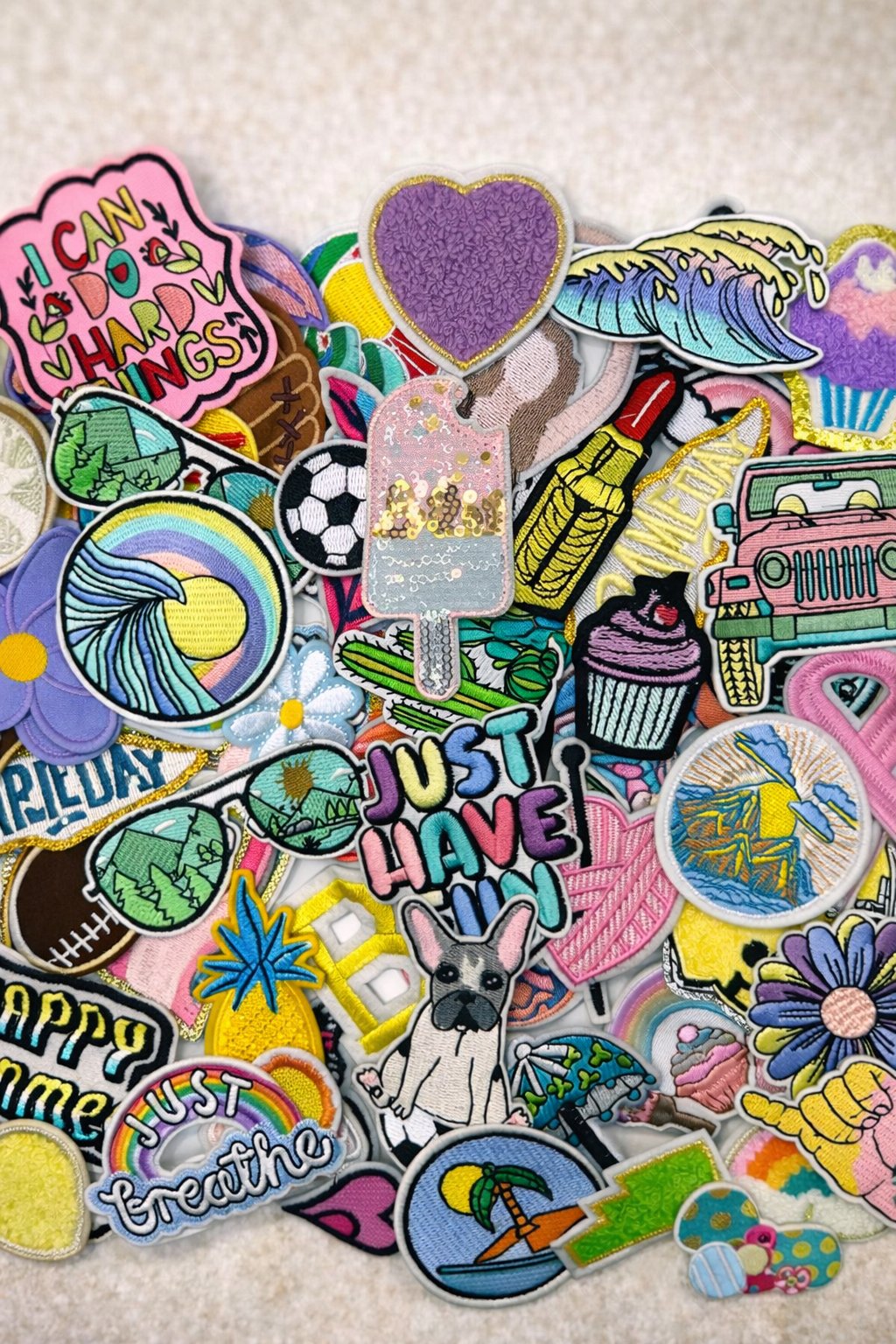 Large collection of colorful iron-on patches spread out for kids to choose from — Sleepover Club Timonium MD