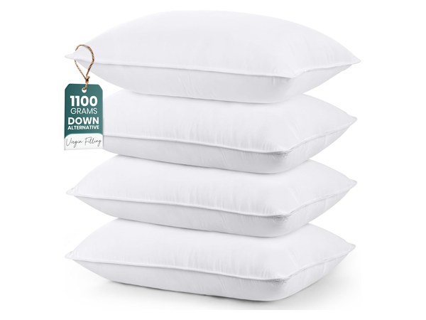 Set of four white bed pillows stacked for sleepover guests