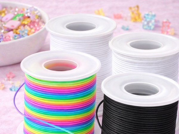 Rolls of stretchy bracelet cord with scissors and beading needle