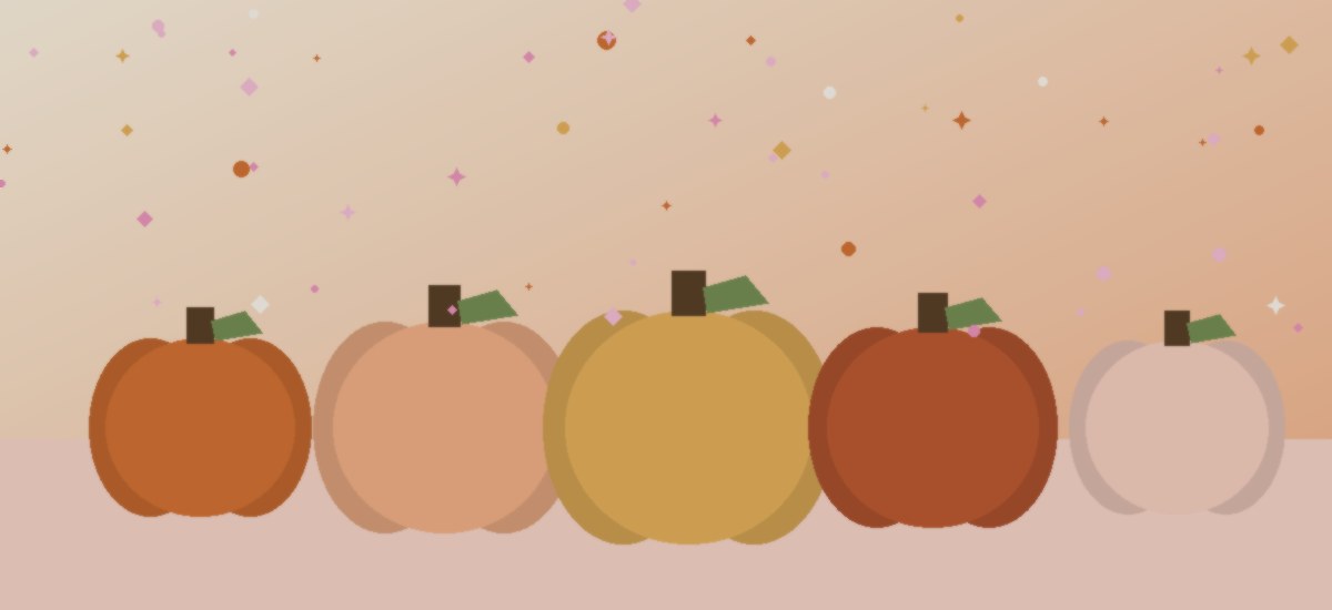 A row of small painted pumpkins in cream, blush, and rust sitting on a fall-toned table