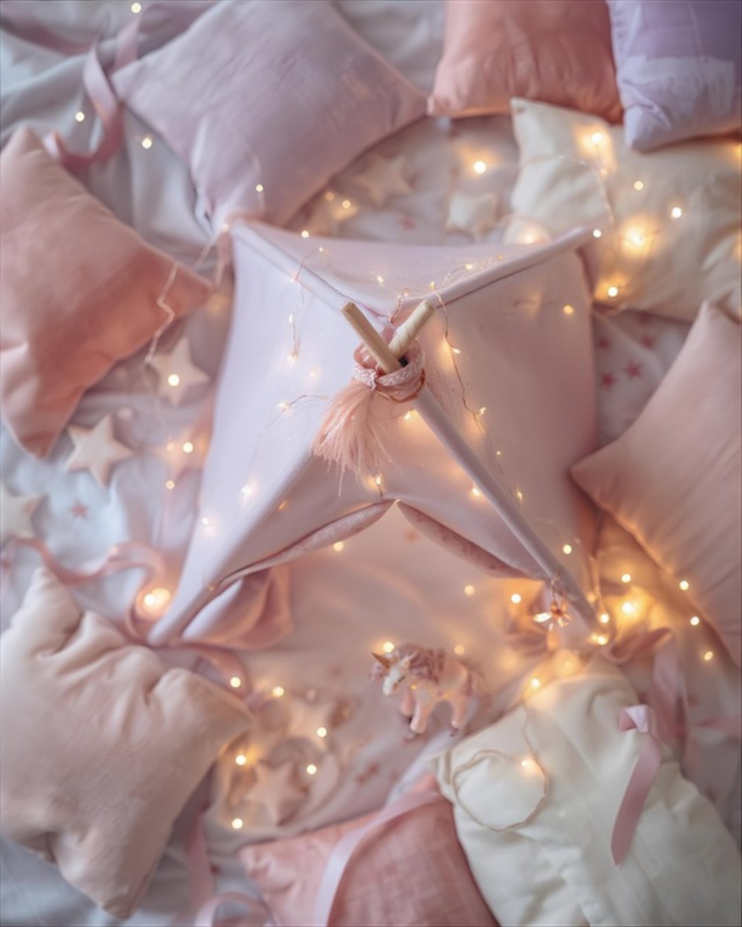 A styled teepee sleepover setup with themed decor, fairy lights, and cozy bedding